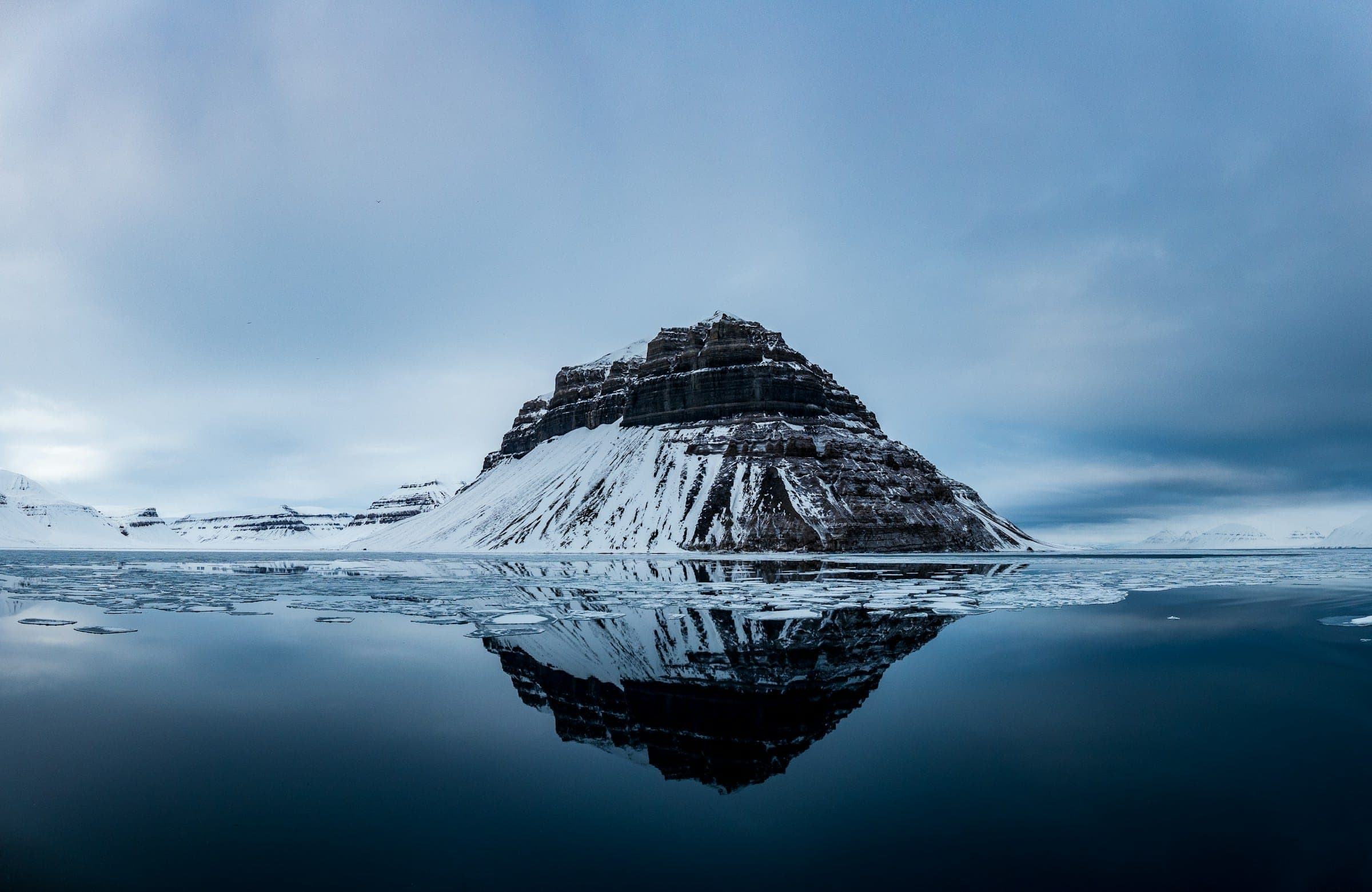 Besneeuwde berg weerspiegeld in het water van de Billefjorden, Spitsbergen
