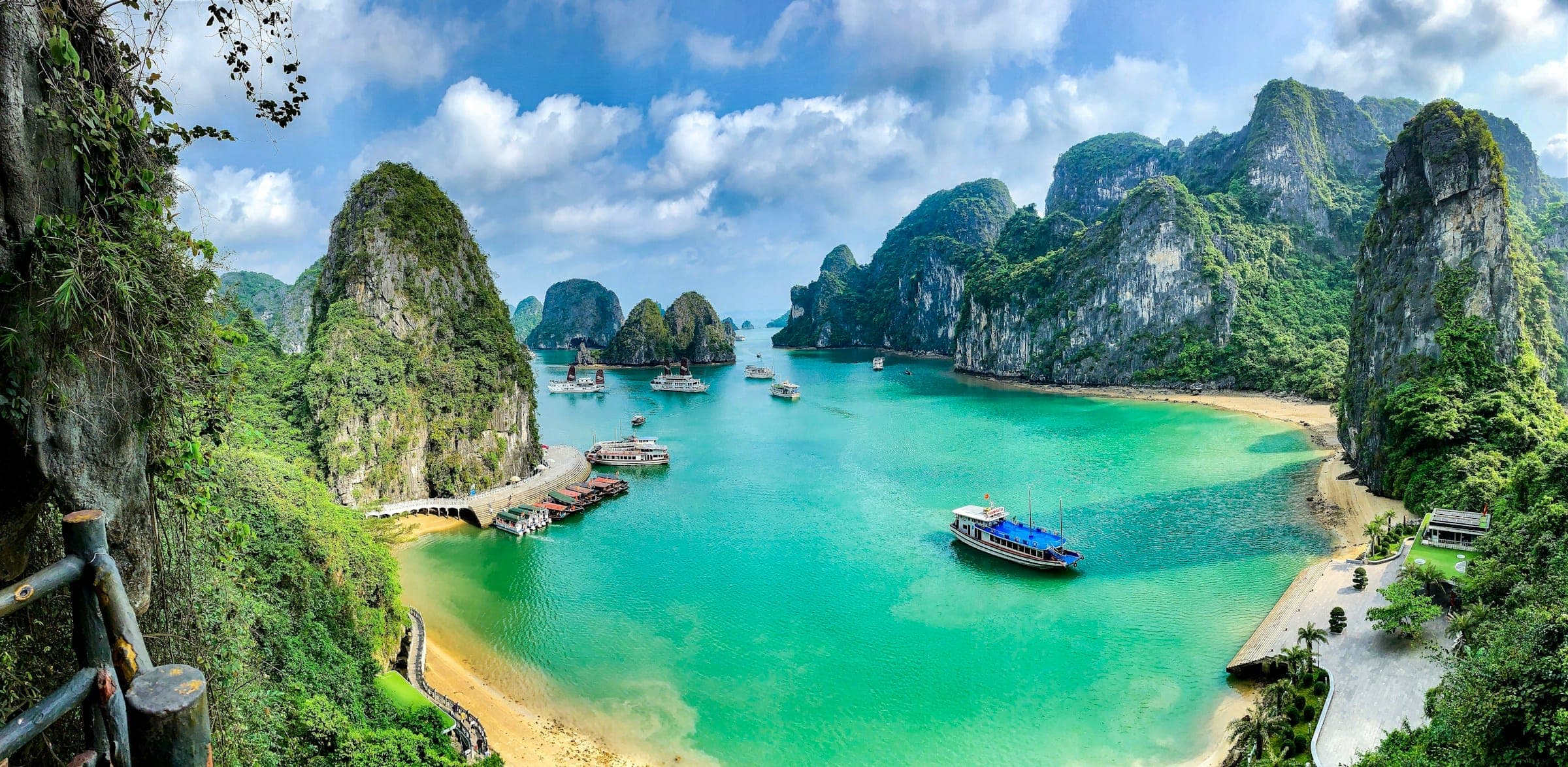 Boten op het turquoise water van Halong Bay tussen de kalksteenrotsen