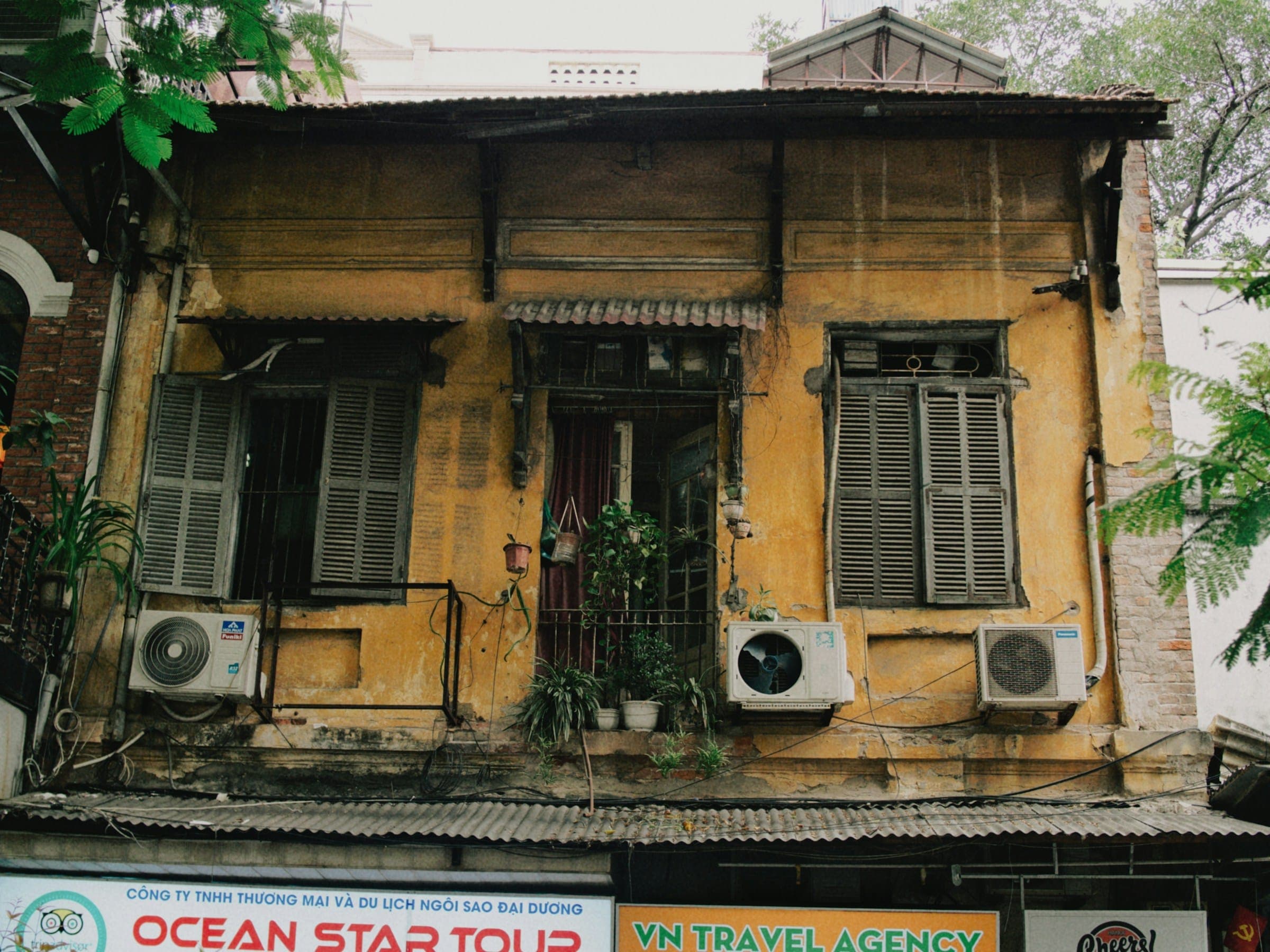 Verweerd geel huis met houten luiken in Hanoi